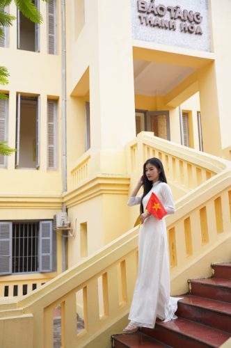 Ảnh bạn nữ mặc áo dài đứng tạo dáng ở bậc thềm.