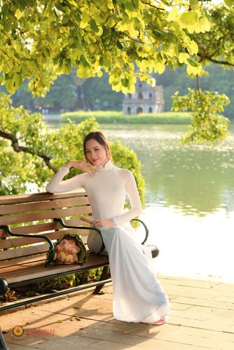 Hình ảnh thiếu nữ mặc áo dài trắng đứng bên hồ Gươm vào mùa thu, lá vàng rơi