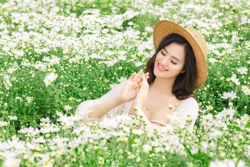 Cô gái đội nón lá, ngắm bó cúc họa mi, cười rạng rỡ giữa vườn hoa