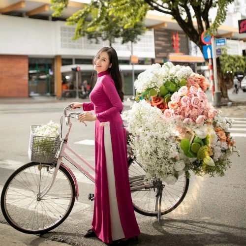 Thiếu nữ mặc áo dài hồng, đứng bên xe hoa hoặc xe đạp, lá vàng mùa thu